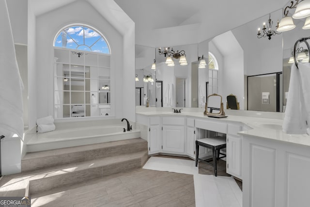 full bath with a sink, a bath, double vanity, lofted ceiling, and a chandelier