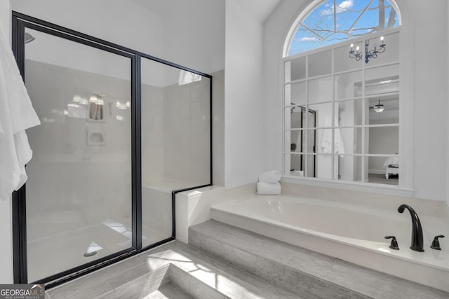 full bathroom featuring a chandelier, a garden tub, and a stall shower