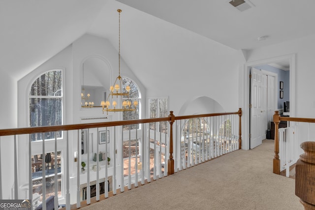 hall with a chandelier, visible vents, carpet, and vaulted ceiling