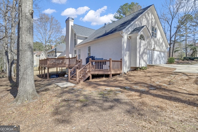 exterior space with a wooden deck, a chimney, a garage, and a shingled roof