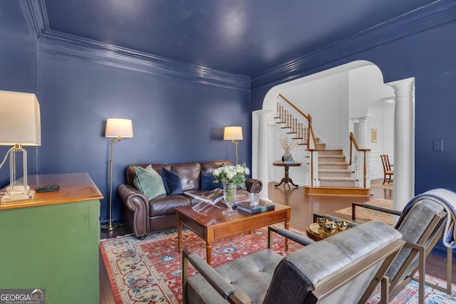 living area featuring decorative columns, arched walkways, ornamental molding, and stairs