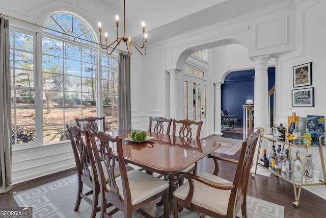 dining area with arched walkways, a decorative wall, plenty of natural light, and decorative columns