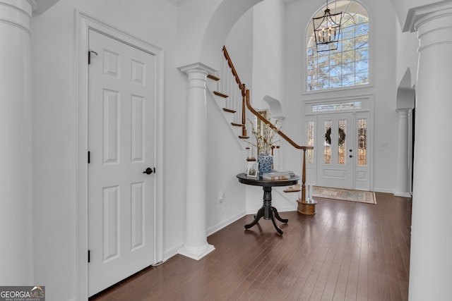 entryway with arched walkways, dark wood-style flooring, and ornate columns