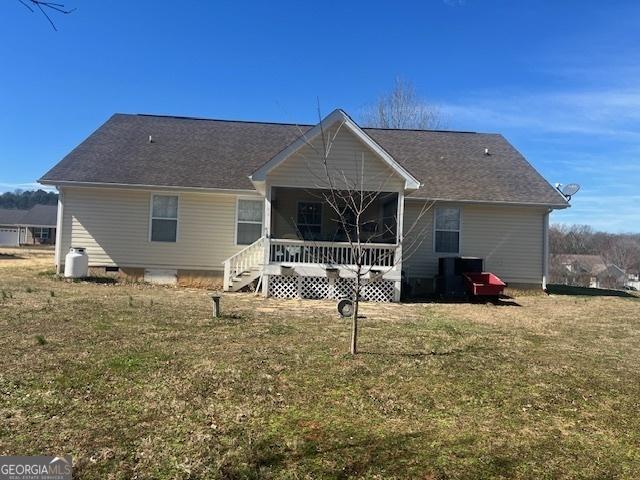 rear view of house featuring a porch and a lawn