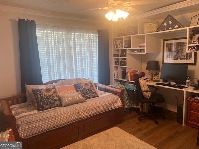 bedroom featuring ornamental molding, wood finished floors, and a ceiling fan