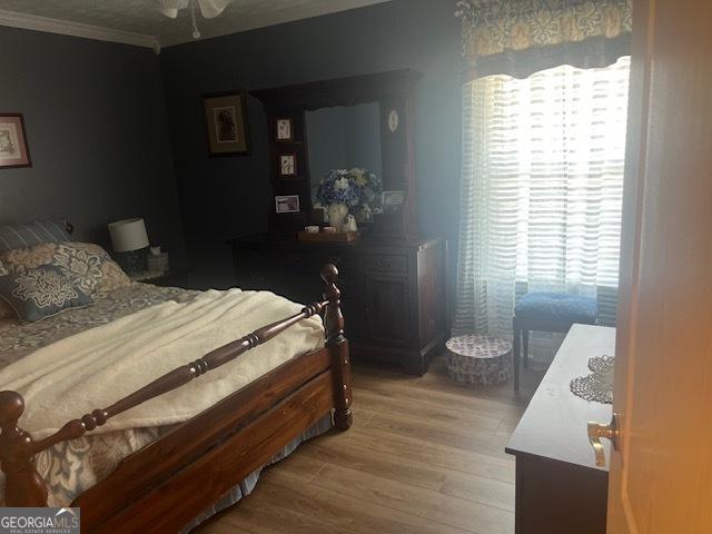 bedroom featuring light wood finished floors and crown molding