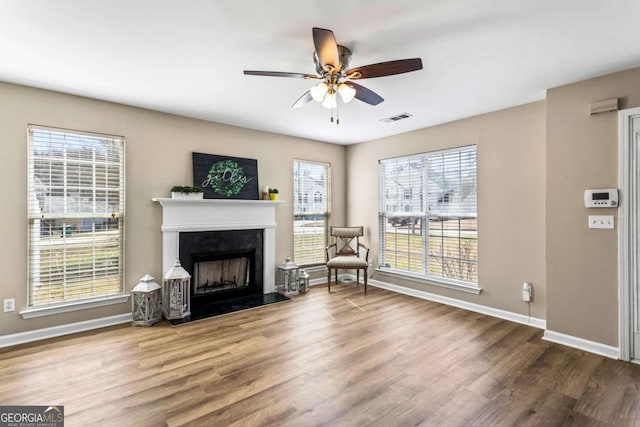 living area with a healthy amount of sunlight, visible vents, a fireplace, and wood finished floors