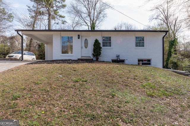 ranch-style house with driveway, brick siding, and a front yard