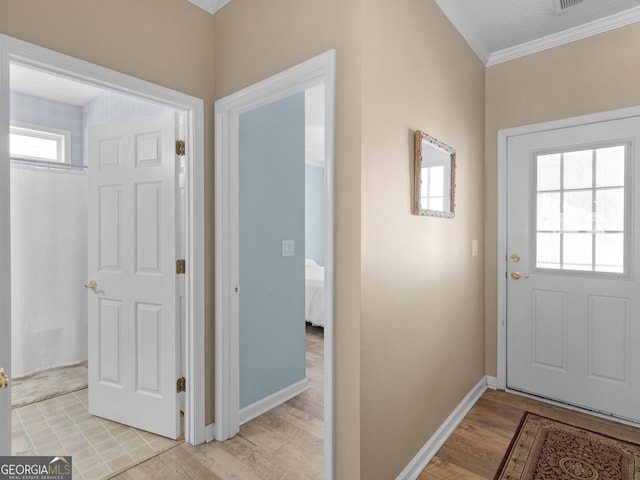 doorway to outside with baseboards, light wood-type flooring, and crown molding