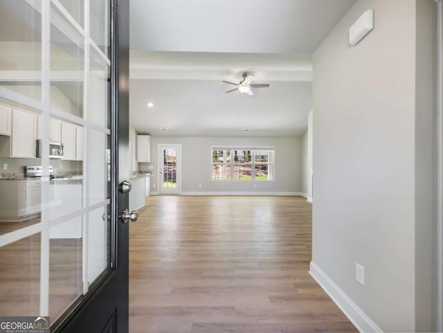 unfurnished living room featuring light wood finished floors, ceiling fan, and baseboards