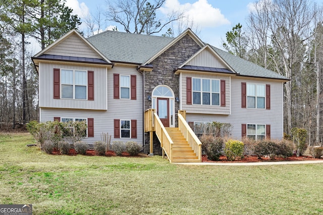 bi-level home featuring a standing seam roof, a front yard, and a shingled roof