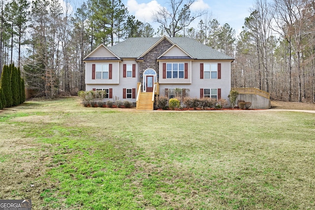 raised ranch featuring a front yard, stone siding, and roof with shingles