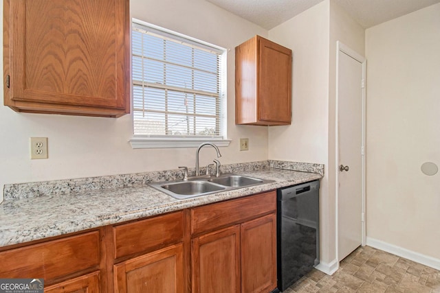 kitchen with brown cabinetry, baseboards, a sink, light countertops, and black dishwasher