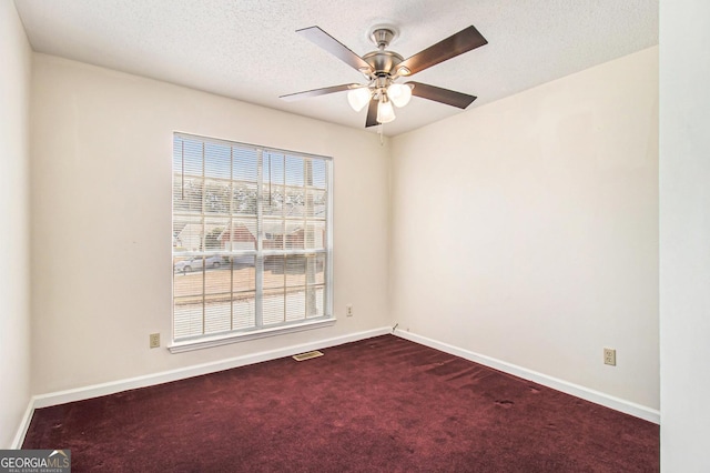 empty room with visible vents, baseboards, a textured ceiling, a ceiling fan, and dark colored carpet