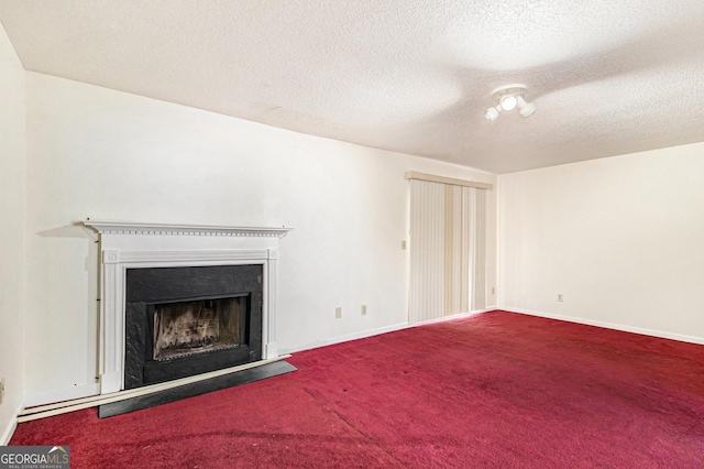 unfurnished living room featuring baseboards, carpet, a fireplace, and a textured ceiling