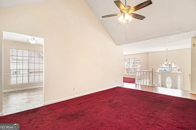 spare room featuring baseboards, high vaulted ceiling, carpet flooring, ceiling fan with notable chandelier, and a textured ceiling