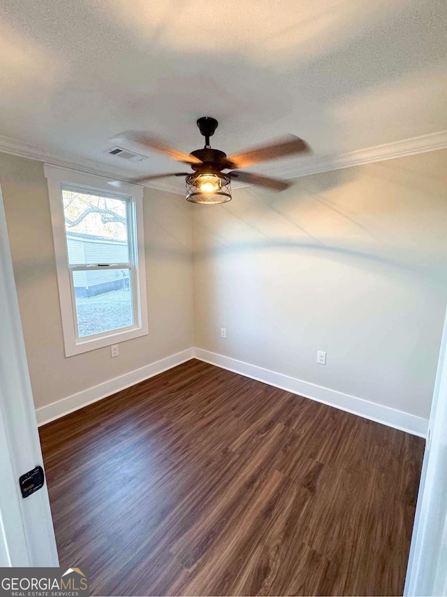 spare room featuring a textured ceiling, dark wood-type flooring, visible vents, baseboards, and crown molding