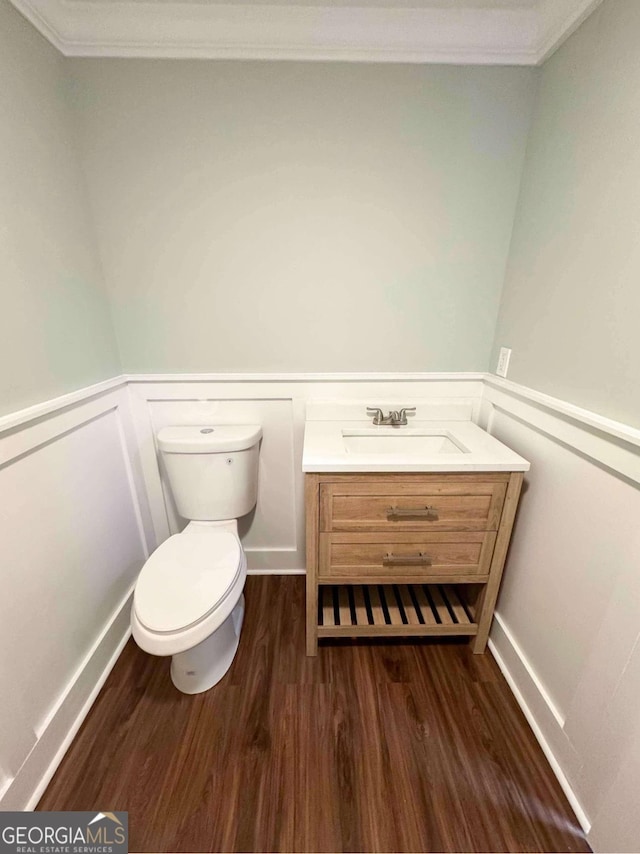 bathroom with wainscoting, toilet, wood finished floors, crown molding, and vanity