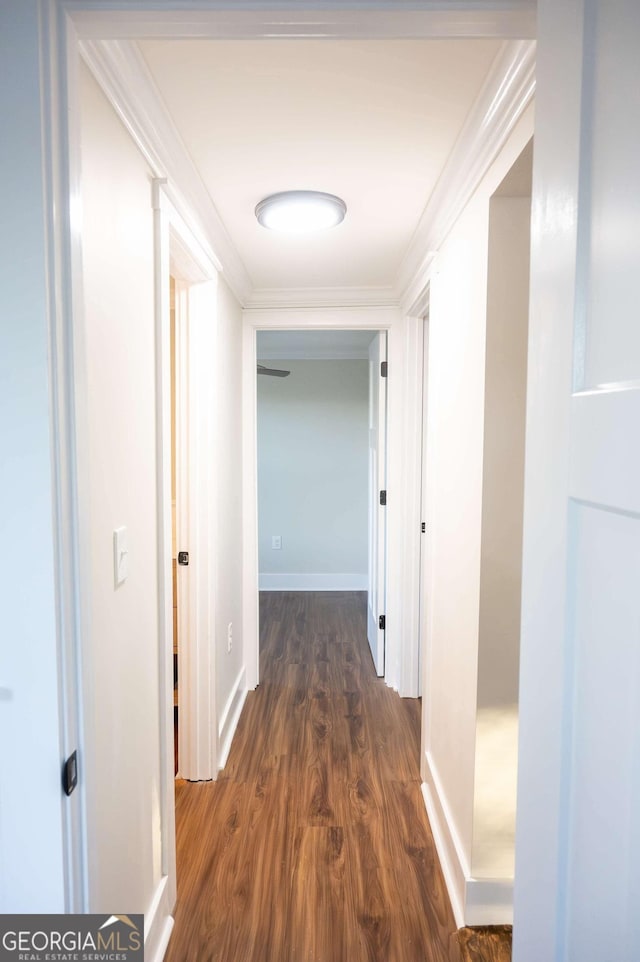 corridor featuring dark wood-style floors, crown molding, and baseboards