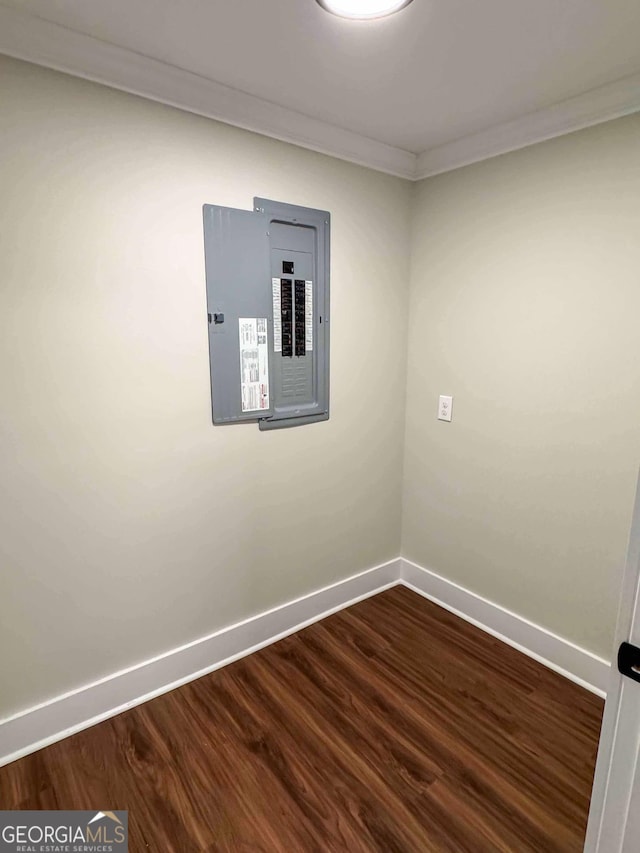 empty room featuring electric panel, dark wood finished floors, and baseboards