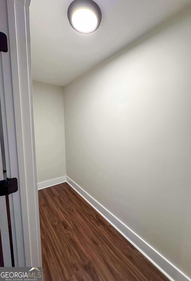 spare room featuring dark wood-style floors and baseboards