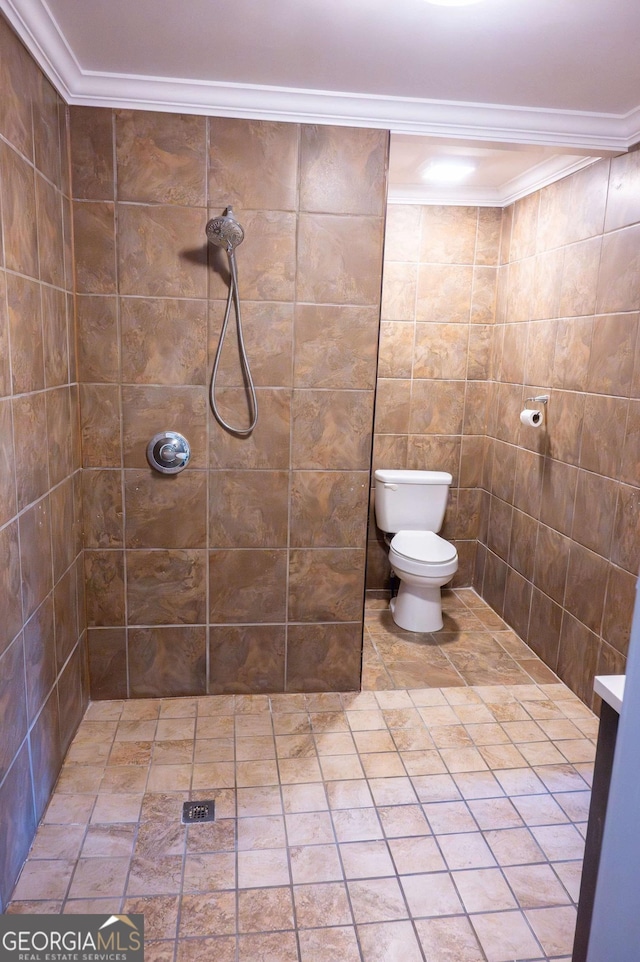 bathroom with toilet, ornamental molding, and a tile shower