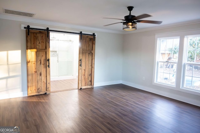 spare room featuring a wealth of natural light, a barn door, visible vents, and crown molding