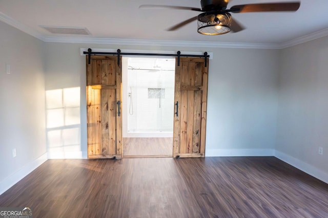 empty room with a barn door, baseboards, visible vents, ornamental molding, and wood finished floors