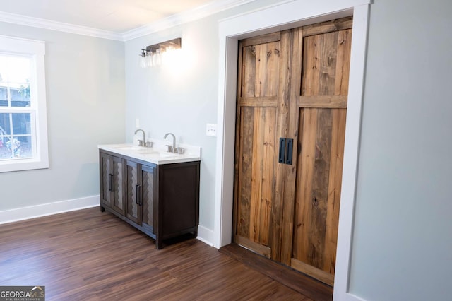 bathroom with a sink, baseboards, ornamental molding, and wood finished floors