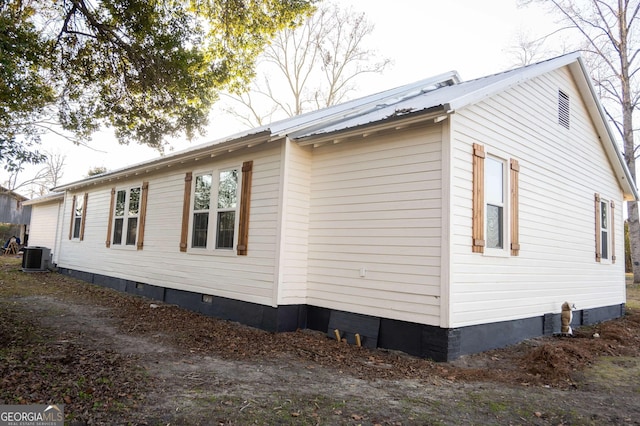 view of home's exterior with metal roof, crawl space, and central AC