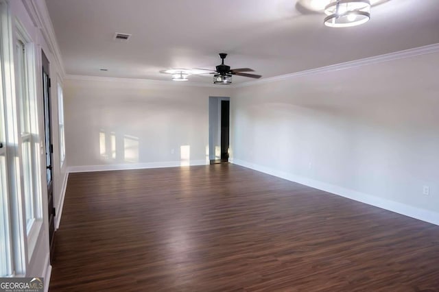 empty room with ceiling fan, visible vents, dark wood finished floors, and ornamental molding