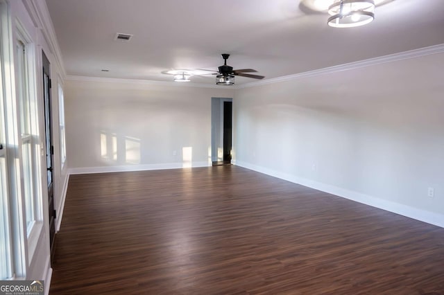 empty room featuring ornamental molding, dark wood-style flooring, visible vents, and a ceiling fan