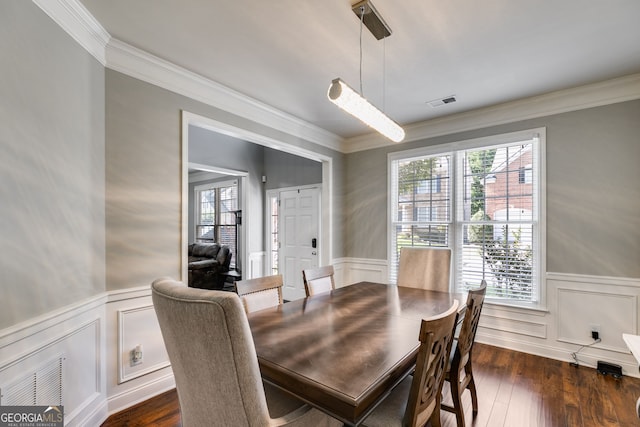 dining area with wainscoting, crown molding, and dark wood-style flooring