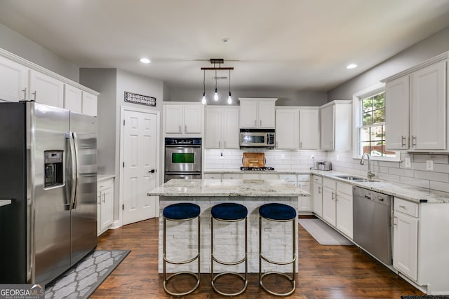 kitchen featuring a sink, decorative backsplash, appliances with stainless steel finishes, and a center island