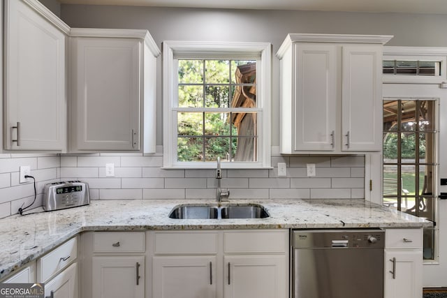 kitchen featuring a sink, tasteful backsplash, stainless steel dishwasher, and white cabinetry