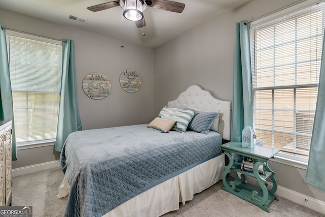 bedroom with visible vents, multiple windows, and light carpet