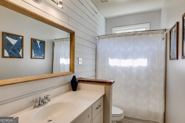 full bathroom featuring visible vents, toilet, curtained shower, wooden walls, and vanity