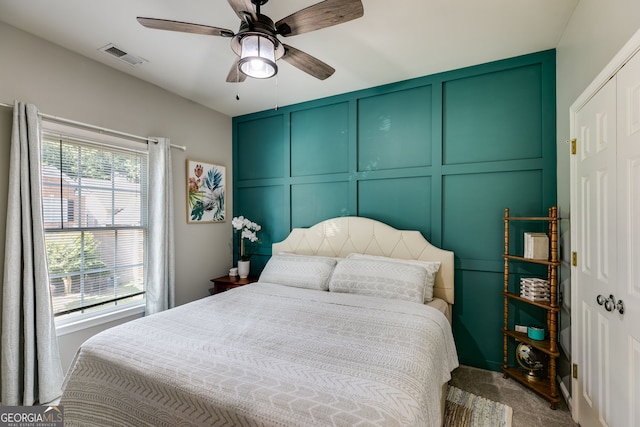 bedroom featuring a decorative wall, a ceiling fan, and visible vents