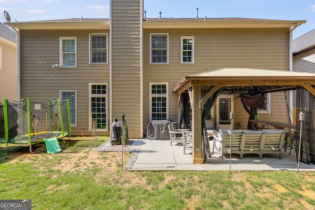 rear view of property featuring a gazebo, a patio area, an outdoor hangout area, and a trampoline