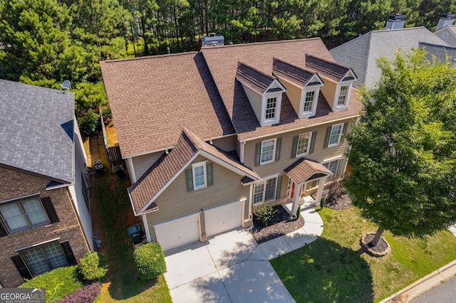 view of front of property with a shingled roof, a front lawn, a chimney, a garage, and driveway