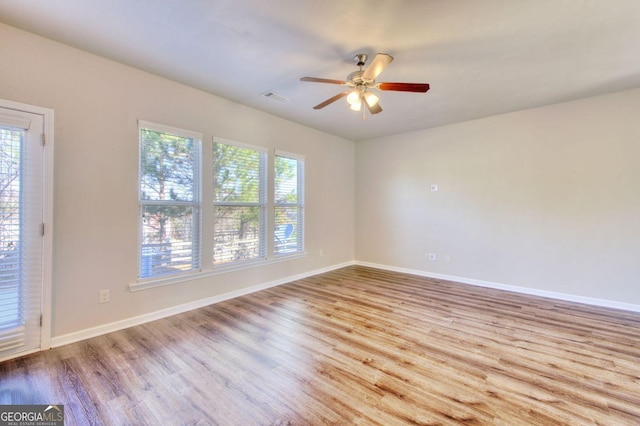 unfurnished room featuring a ceiling fan, wood finished floors, visible vents, and baseboards