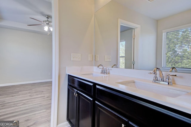 bathroom featuring double vanity, a sink, baseboards, and wood finished floors