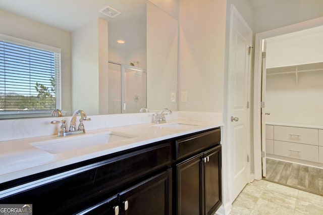 full bathroom featuring double vanity, a sink, visible vents, and a shower stall