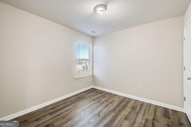 spare room with visible vents, baseboards, and wood finished floors