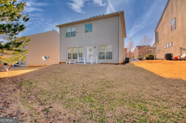 rear view of house featuring central AC unit and a lawn