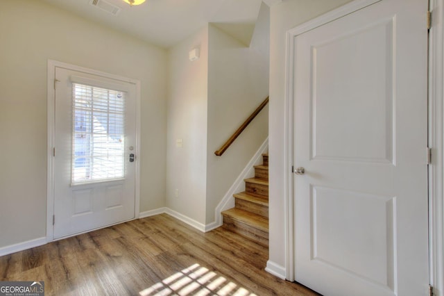 entryway featuring baseboards, visible vents, stairway, and wood finished floors