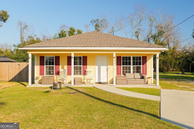 bungalow featuring covered porch, a shingled roof, fence, and a front lawn