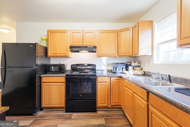 kitchen featuring a textured ceiling, under cabinet range hood, a sink, dark wood-style floors, and black appliances