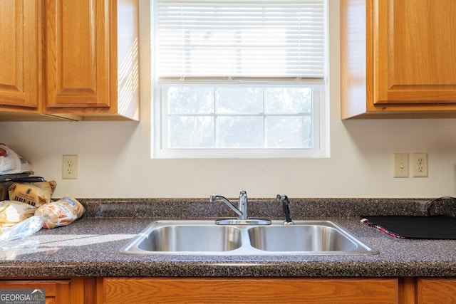 kitchen with dark countertops, a sink, and brown cabinets