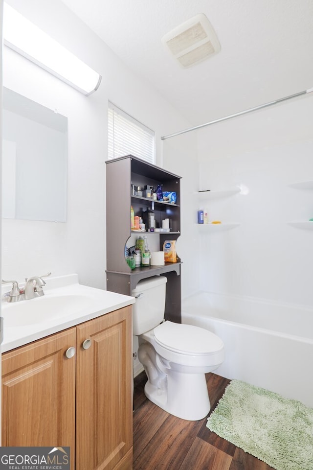 full bathroom with washtub / shower combination, vanity, toilet, and wood finished floors